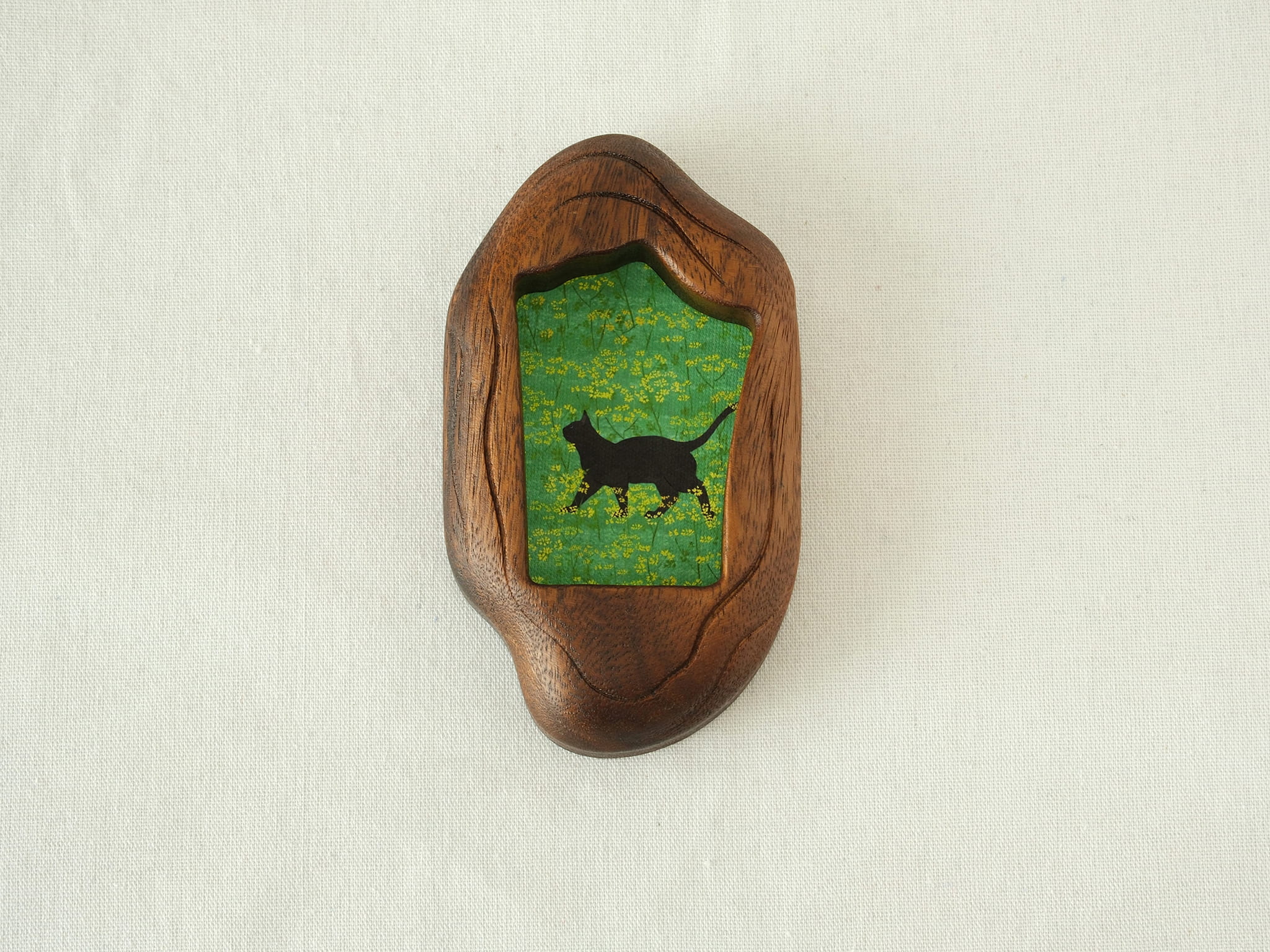 Front view of the Irregular Organic handmade solid wood art frame, featuring a charming illustration of a black cat walking through a field of yellow flowers.