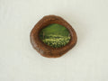 Front view of the lake-shaped organic solid wood frame, featuring a serene landscape painting of a green meadow filled with white wildflowers.
