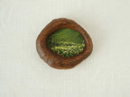 Front view of the lake-shaped organic solid wood frame, featuring a serene landscape painting of a green meadow filled with white wildflowers.