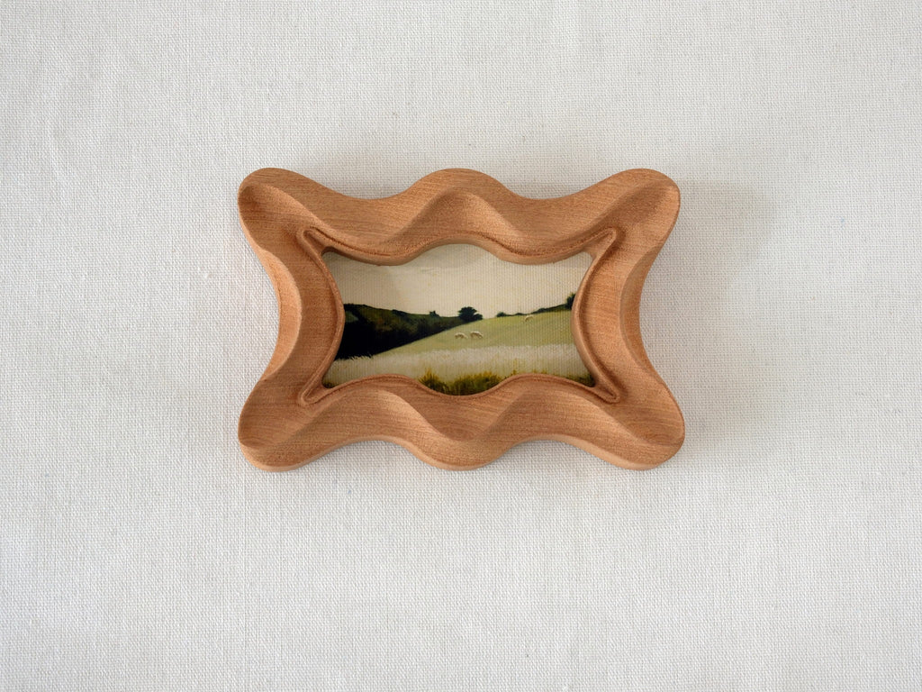 Front view of a rippled wave wood frame, featuring fluid organic edges and a hand-sculpted sculptural silhouette.