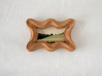Front view of a rippled wave wood frame, featuring fluid organic edges and a hand-sculpted sculptural silhouette.