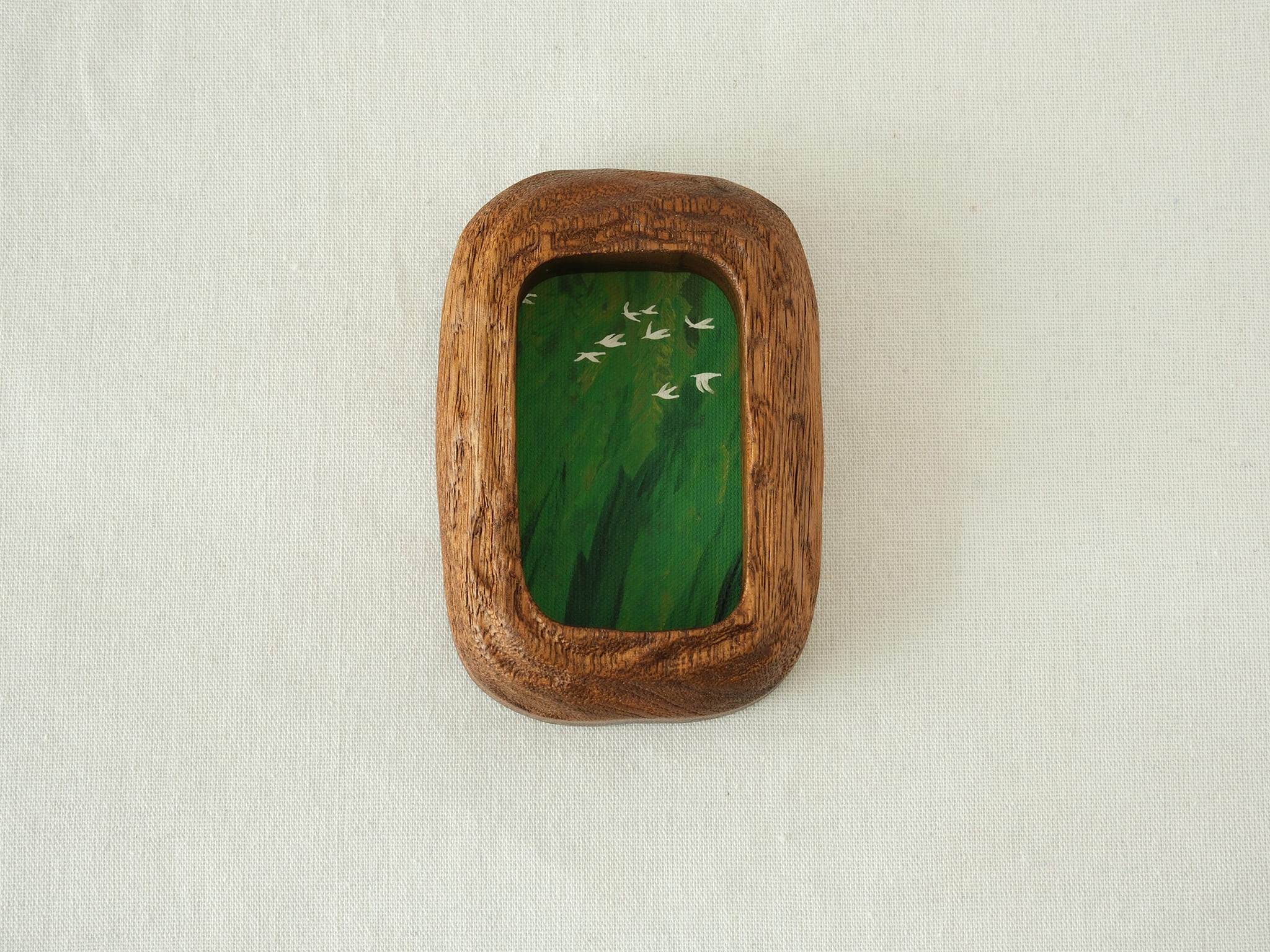 Front view of the Rounded Rectangle handmade solid wood art frame in a vertical orientation, featuring a painting of white birds flying over a dense green forest.