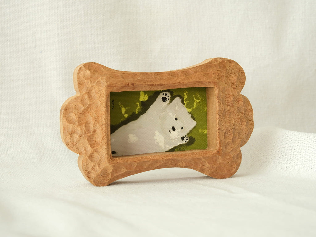 Side-angled view of the bone-shaped wood frame, showcasing its thick profile and hand-chiselled texture on a white backdrop.