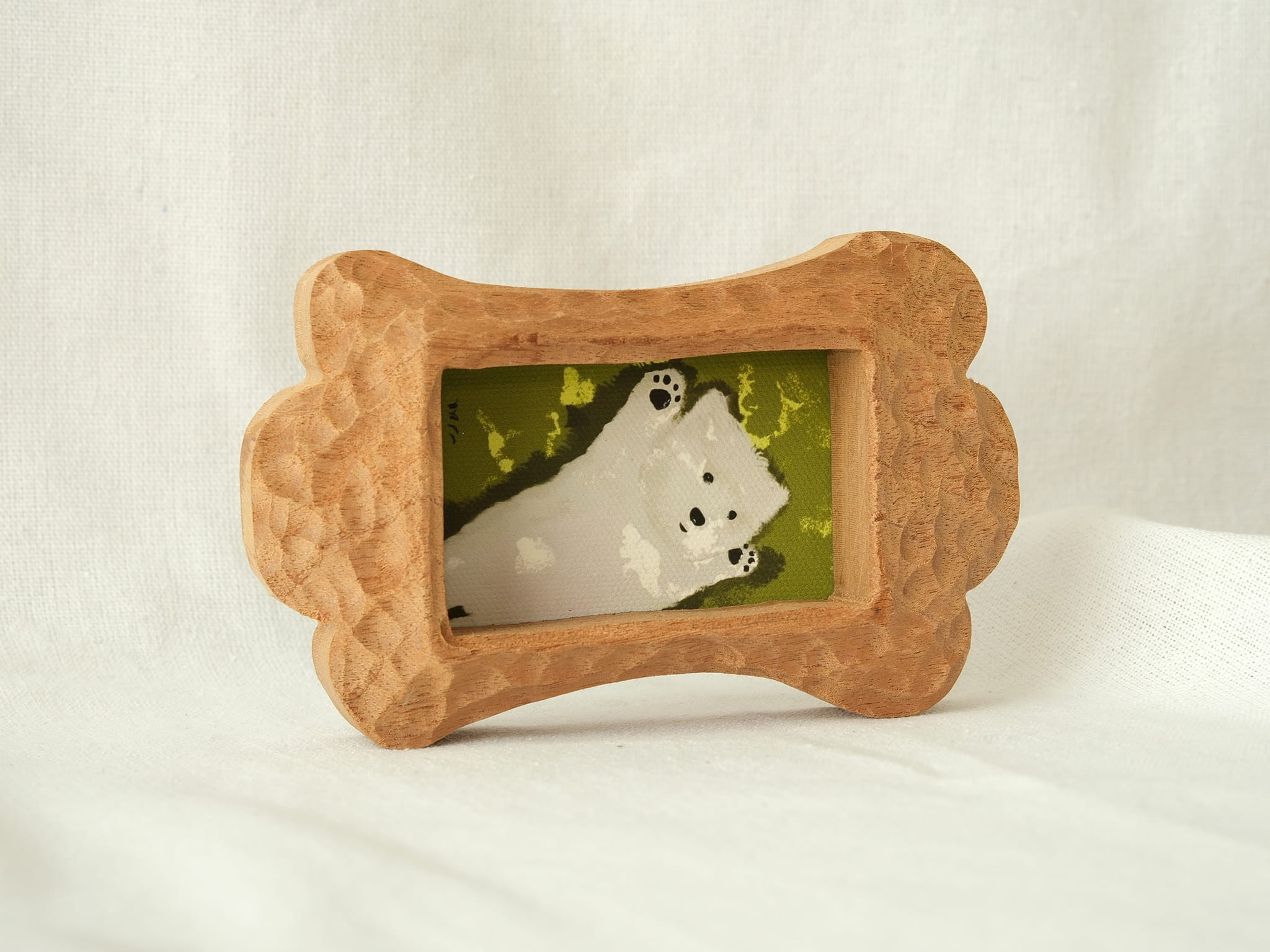 Side-angled view of the bone-shaped wood frame, showcasing its thick profile and hand-chiselled texture on a white backdrop.