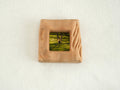 Front view of a handmade square mini picture frame with "Moderno Organico" wavy hand-carved edges, showcasing the rich reddish-brown texture of solid wood and a serene mossy forest painting.