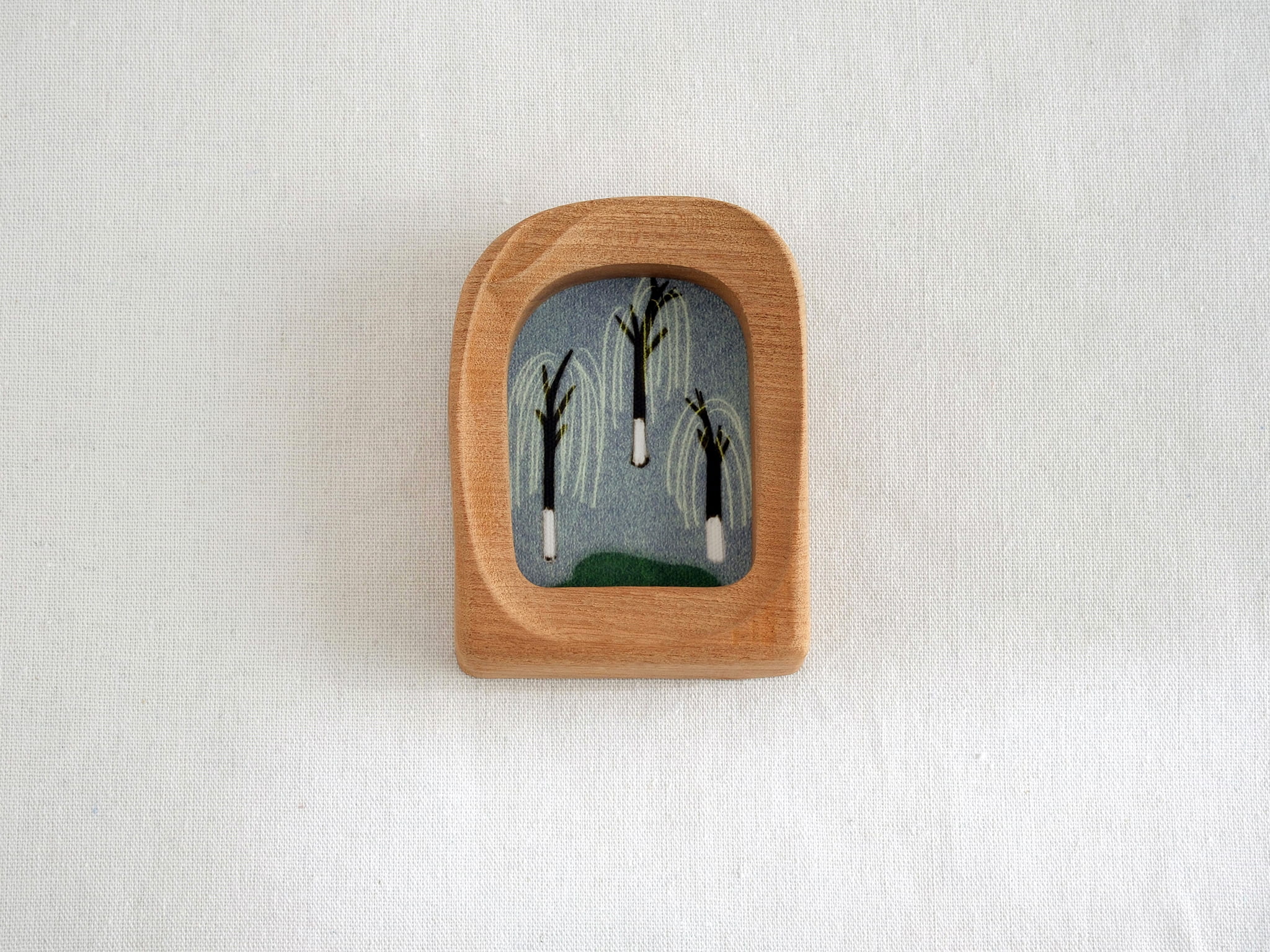 Front view of a soft arched wood frame, featuring a wide organic silhouette and smooth hand-sculpted texture.