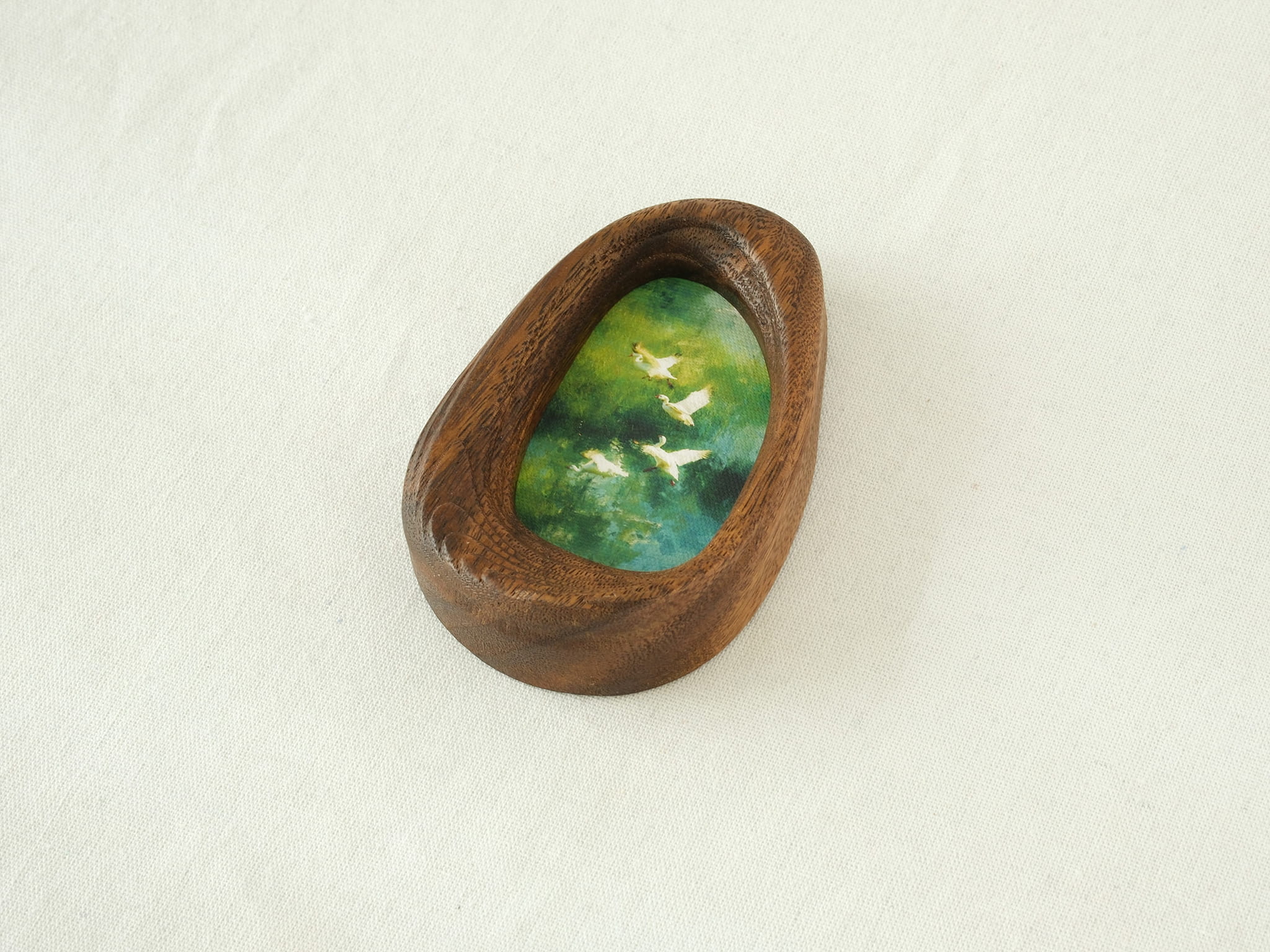 Side view of the Waterdrop handmade solid wood art frame, showcasing the thick pebble-like profile, smooth hand-polished edges, and the depth of the forest birds artwork.