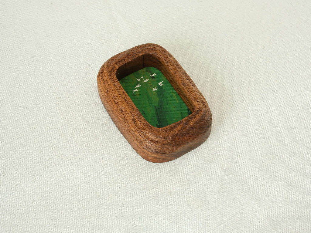 Angled top-down view of the rounded rectangle solid wood frame, showing the deep-set art chamber and the bold, natural grain of the thick timber walls