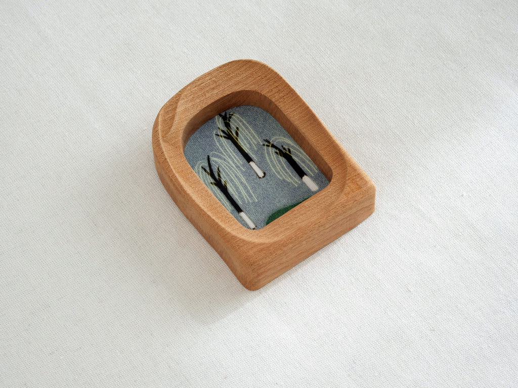 Side angle of the soft arched wood frame, emphasizing its smooth, hand-carved organic curves and warm grain.