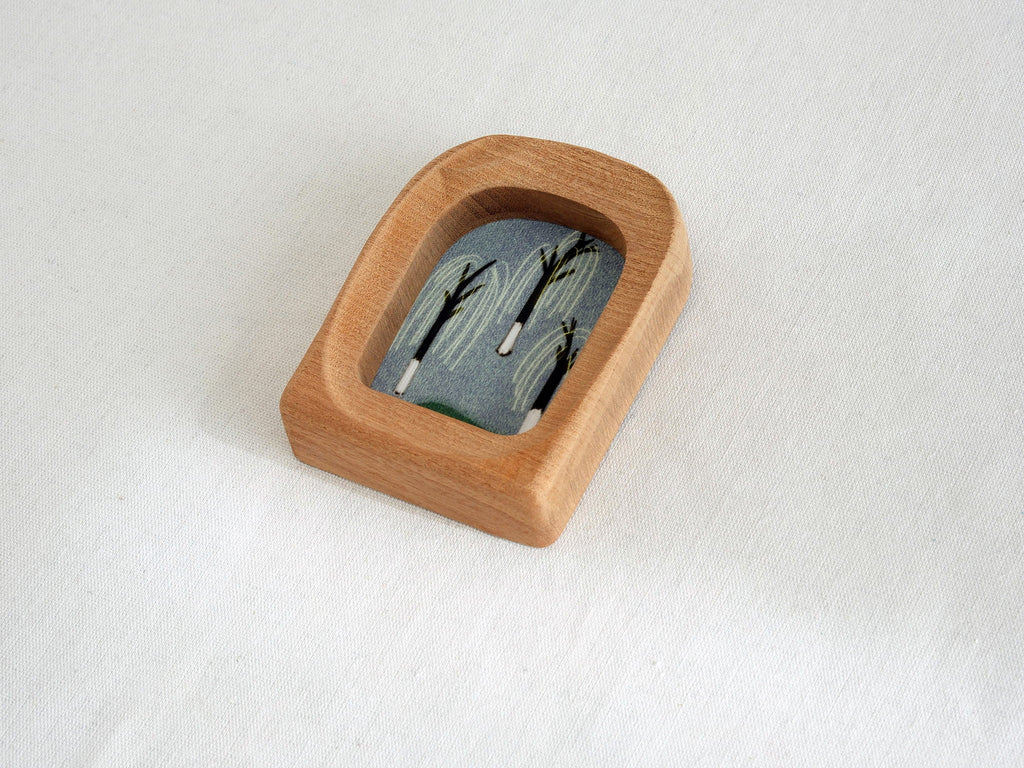 High-angle side view of the soft arched wood frame, displaying its thick organic rim and smooth hand-sculpted finish.