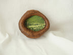 A soft-focus lifestyle shot of the lake-shaped organic wood frame resting on drapes of white fabric, showcasing its sculptural presence as a gentle wall accent with the meadow landscape art.