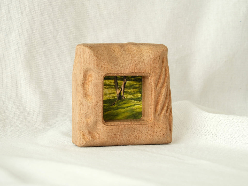 A front-perspective view of the handmade mini square frame standing upright on a white textured surface. The image highlights the frame's stable, thick base and the intricate "Moderno Organico" hand-carved wavy details on the side, creating a sculptural desktop art piece.