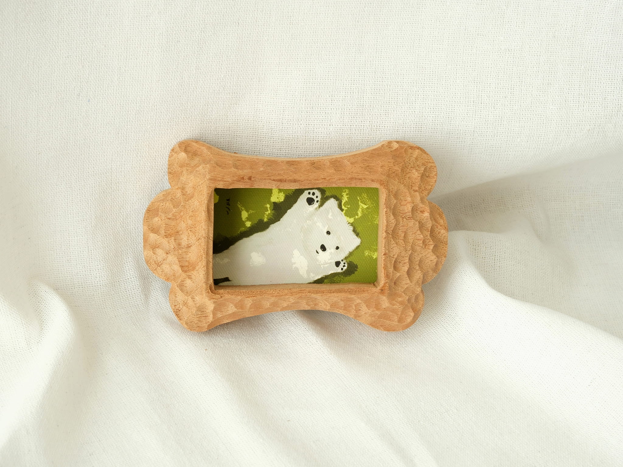 The bone-shaped wood frame leaning against a soft fabric backdrop, showcasing its artistic handcrafted charm as desktop decor.