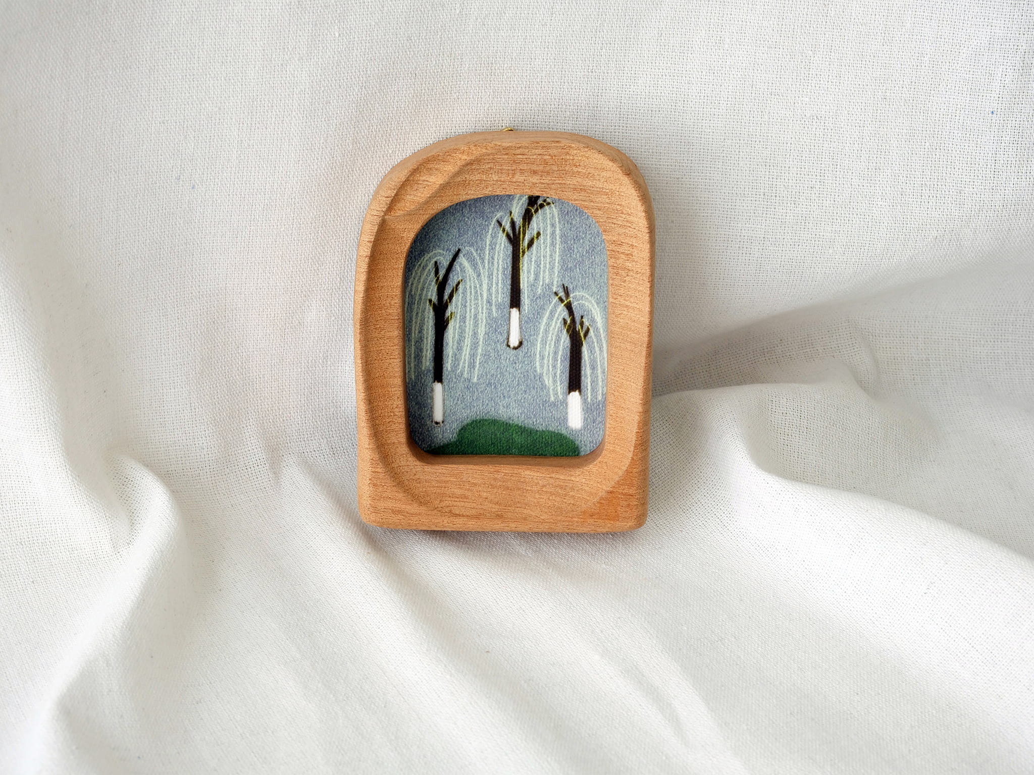 The soft arched wood frame leaning against a soft white draped background, creating a cozy and modern aesthetic.