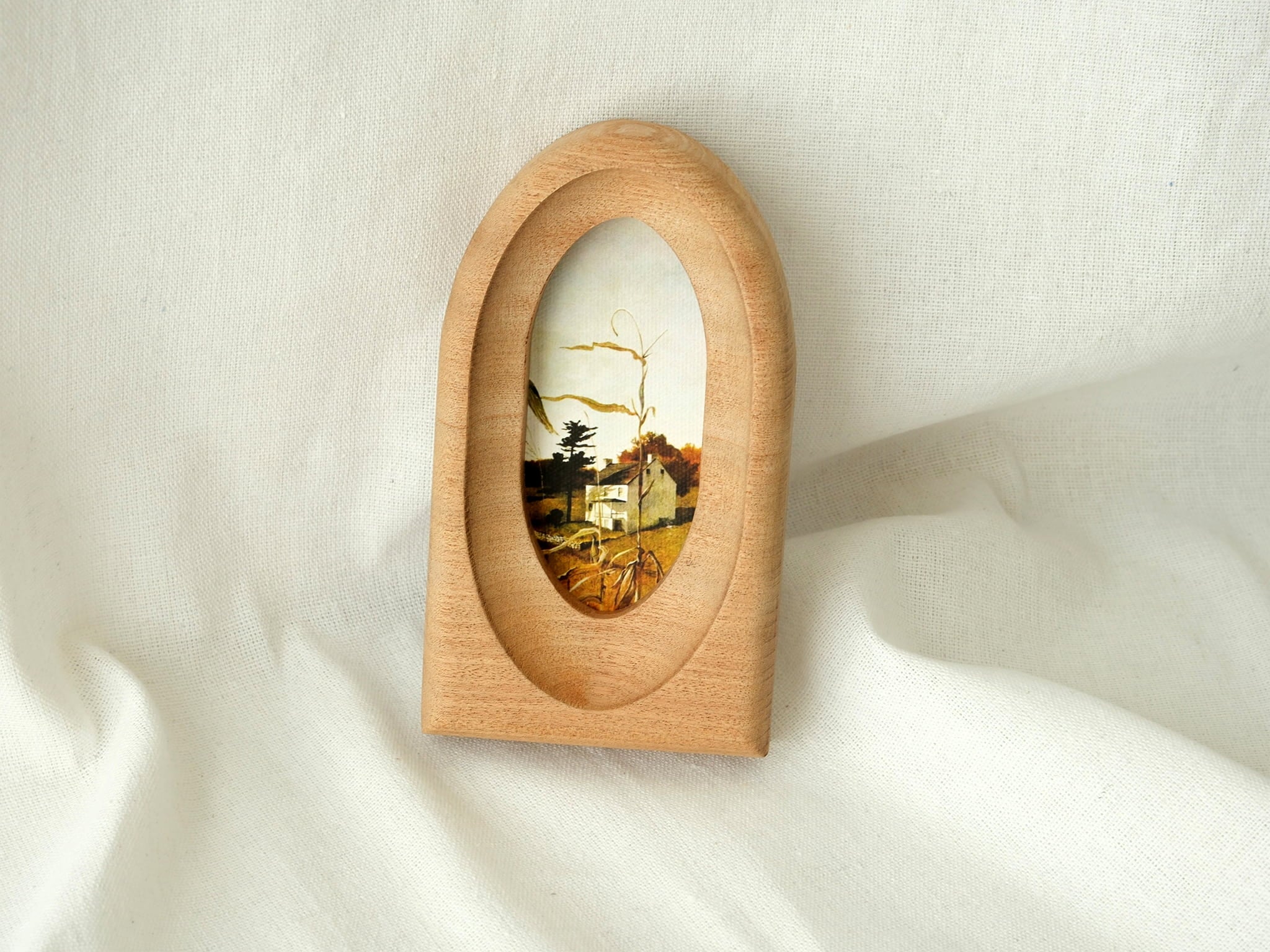 Arched wood art frame leaning against a wall, showcasing its graceful portal silhouette and warm, natural aesthetic.