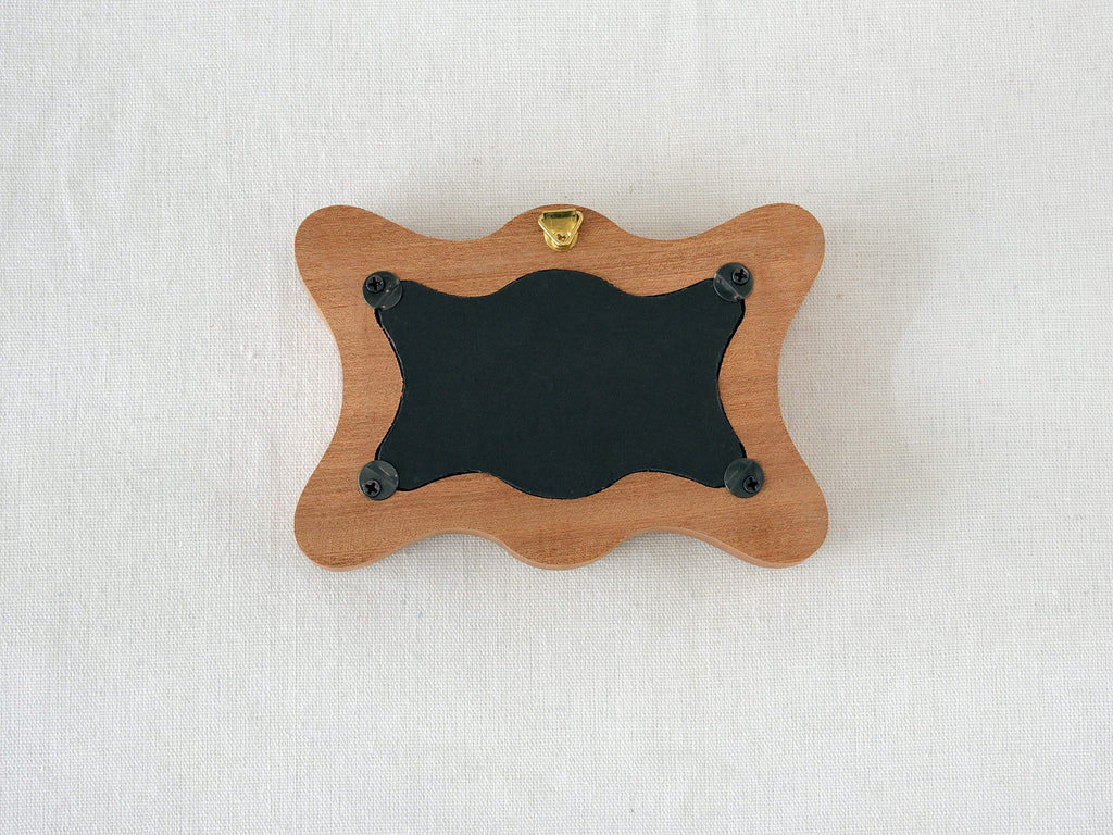 Back view of the rippled wave frame, showing the wall hanger and four secure swivel tabs for easy art replacement.