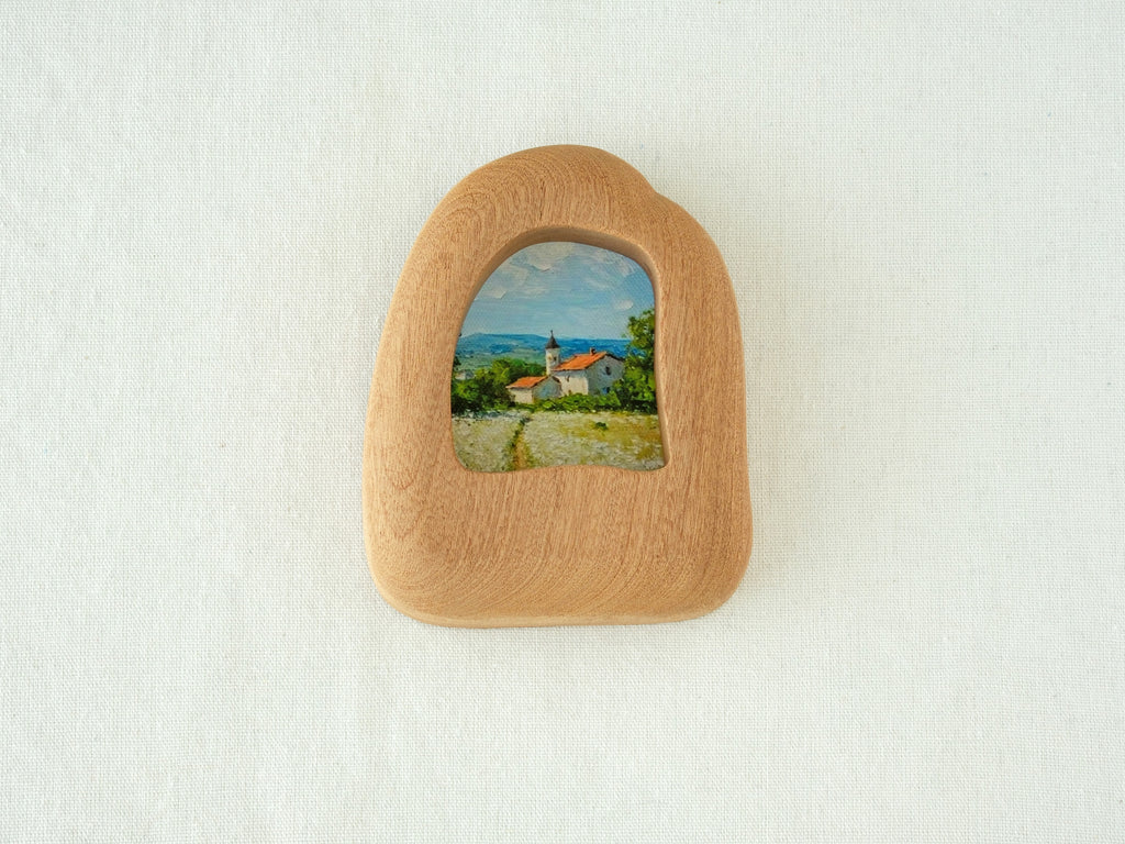 House-shaped wood frame leaning against a soft white textured wall, creating a cozy and natural aesthetic.