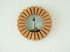 Front view of the sunflower circular solid wood frame with a lighthouse art print, featuring a grooved sunburst design.