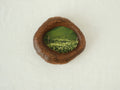 Front view of the lake-shaped organic solid wood frame, featuring a serene landscape painting of a green meadow filled with white wildflowers.