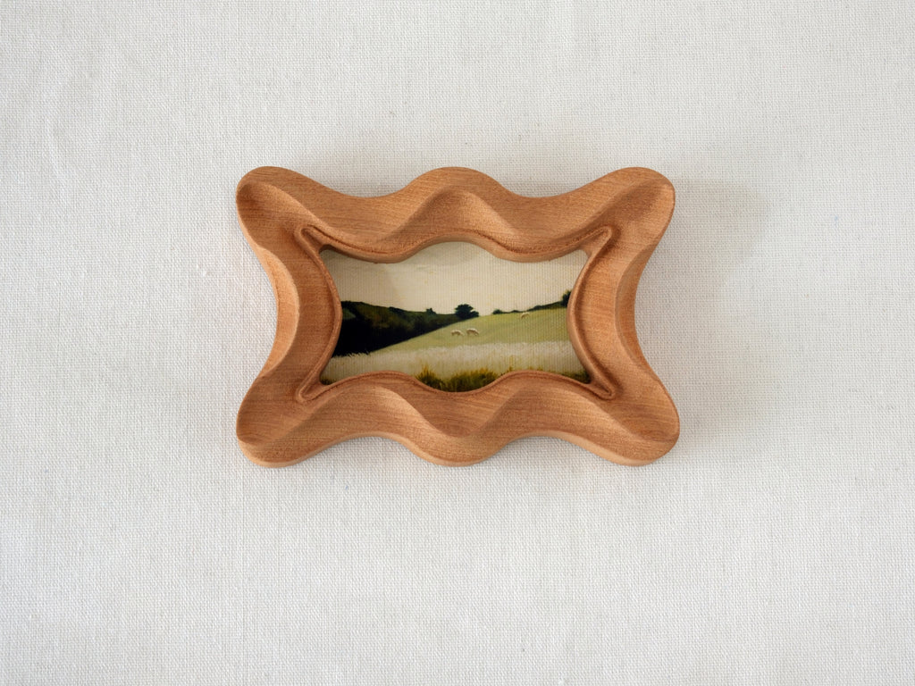 Front view of a rippled wave wood frame, featuring fluid organic edges and a hand-sculpted sculptural silhouette.