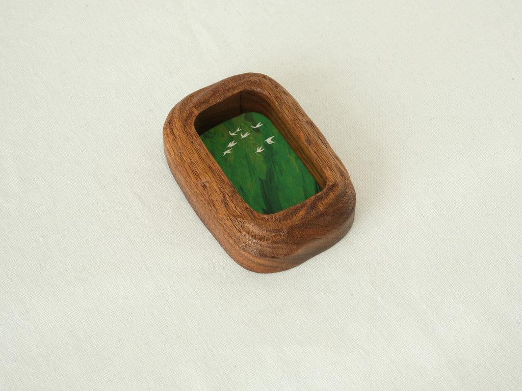 Angled top-down view of the rounded rectangle solid wood frame, showing the deep-set art chamber and the bold, natural grain of the thick timber walls.