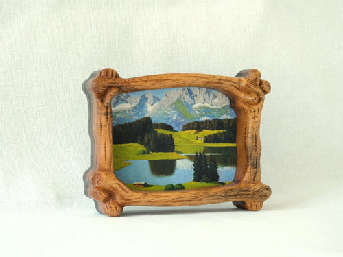 A side-angle view of a handcrafted wood frame with an organic branch-like texture, featuring a vibrant forest sunlight oil painting.