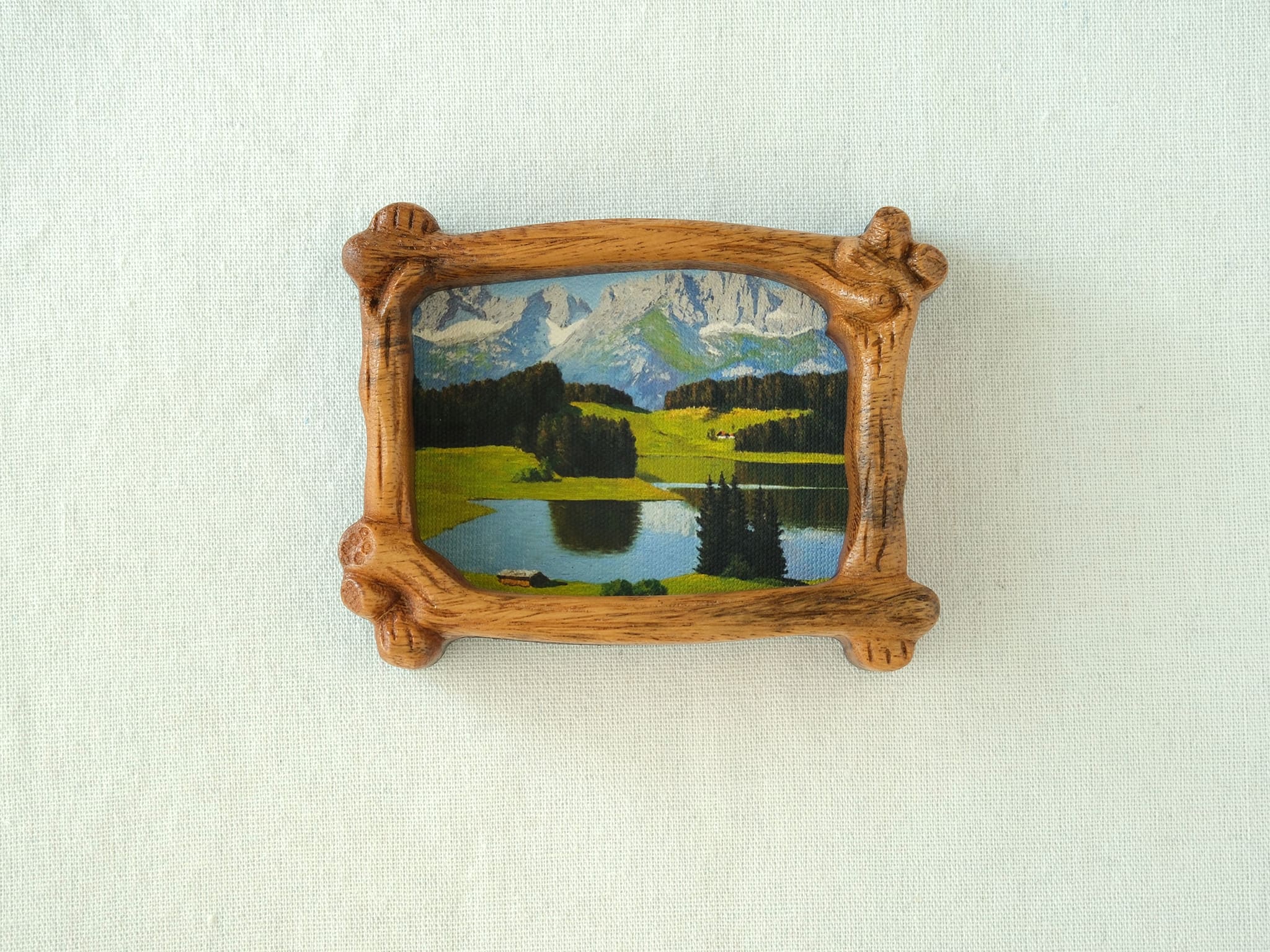 A direct front view of a nature-inspired wood frame with intricate hand-carved bark details, showcasing a lush green forest art piece.