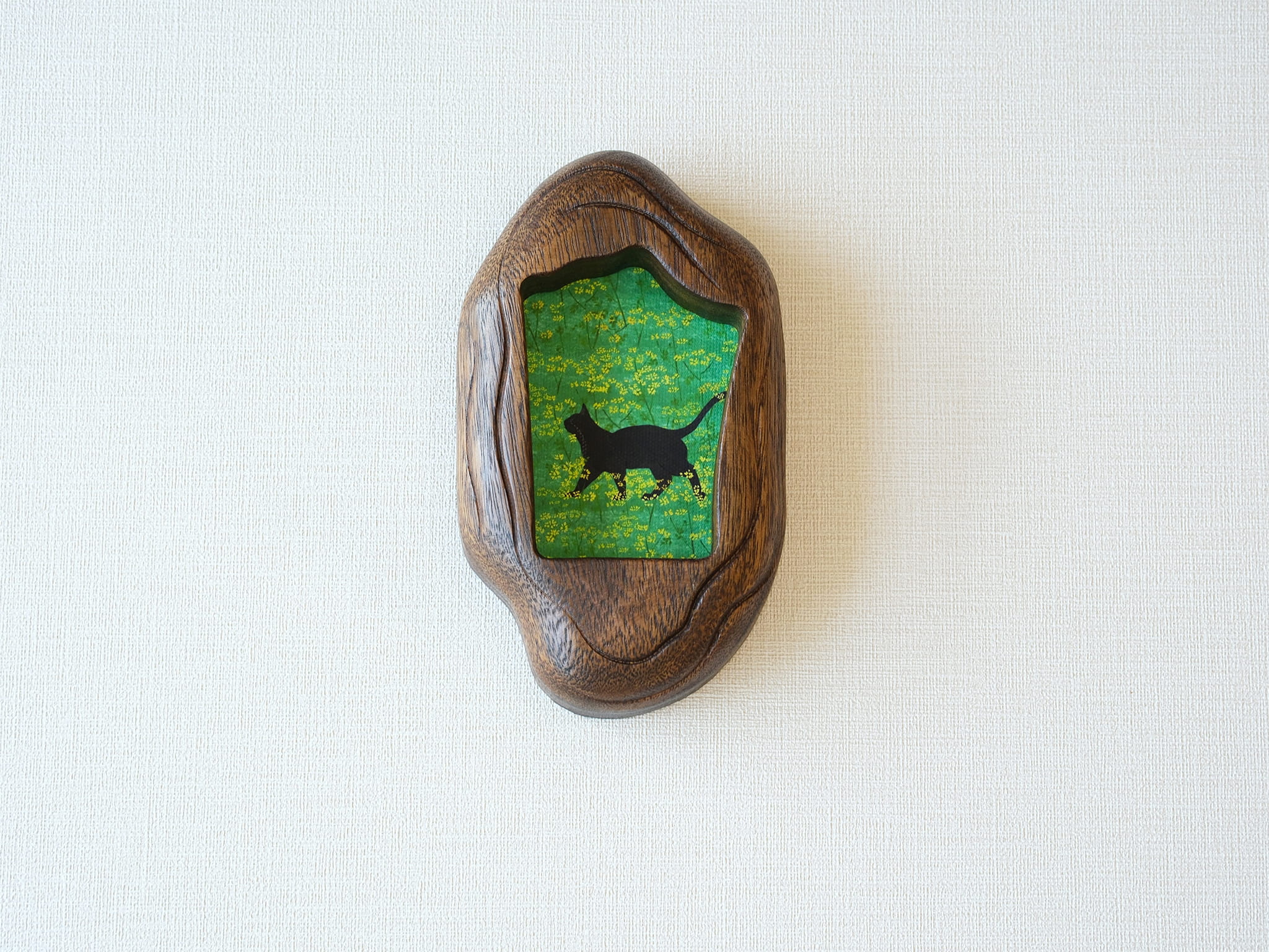 Front view of the Irregular Organic handmade solid wood art frame, featuring a charming illustration of a black cat walking through a field of yellow flowers.