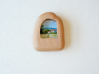 House-shaped wood frame leaning against a soft white textured wall, creating a cozy and natural aesthetic.