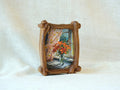 Handcrafted organic shaped solid wood picture frame with a natural grain finish, displayed on a white fabric background as a tabletop decorative art piece.