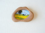 A front view of the handmade solid wood art frame featuring a soft, organic cloud-shaped silhouette. The smooth, hand-sculpted curves of the wood encase a landscape painting, creating the aesthetic of a floating piece of nature.