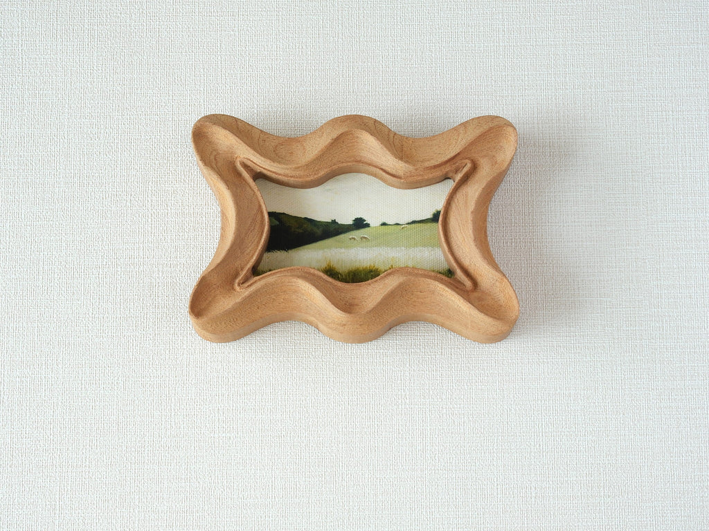 Front view of a rippled wave wood frame, featuring fluid organic edges and a hand-sculpted sculptural silhouette.