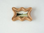 Front view of a rippled wave wood frame, featuring fluid organic edges and a hand-sculpted sculptural silhouette.