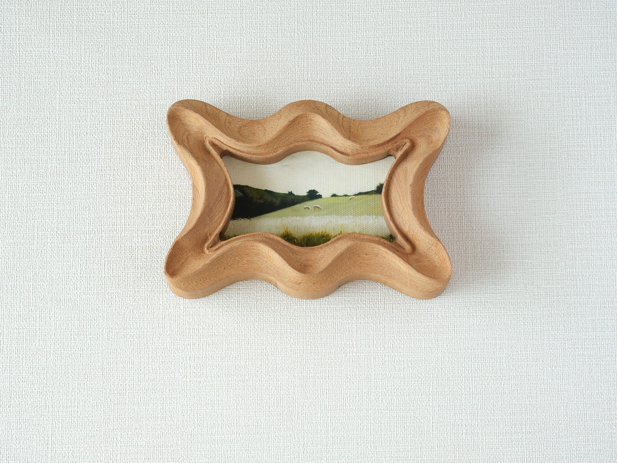 Front view of a rippled wave wood frame, featuring fluid organic edges and a hand-sculpted sculptural silhouette.