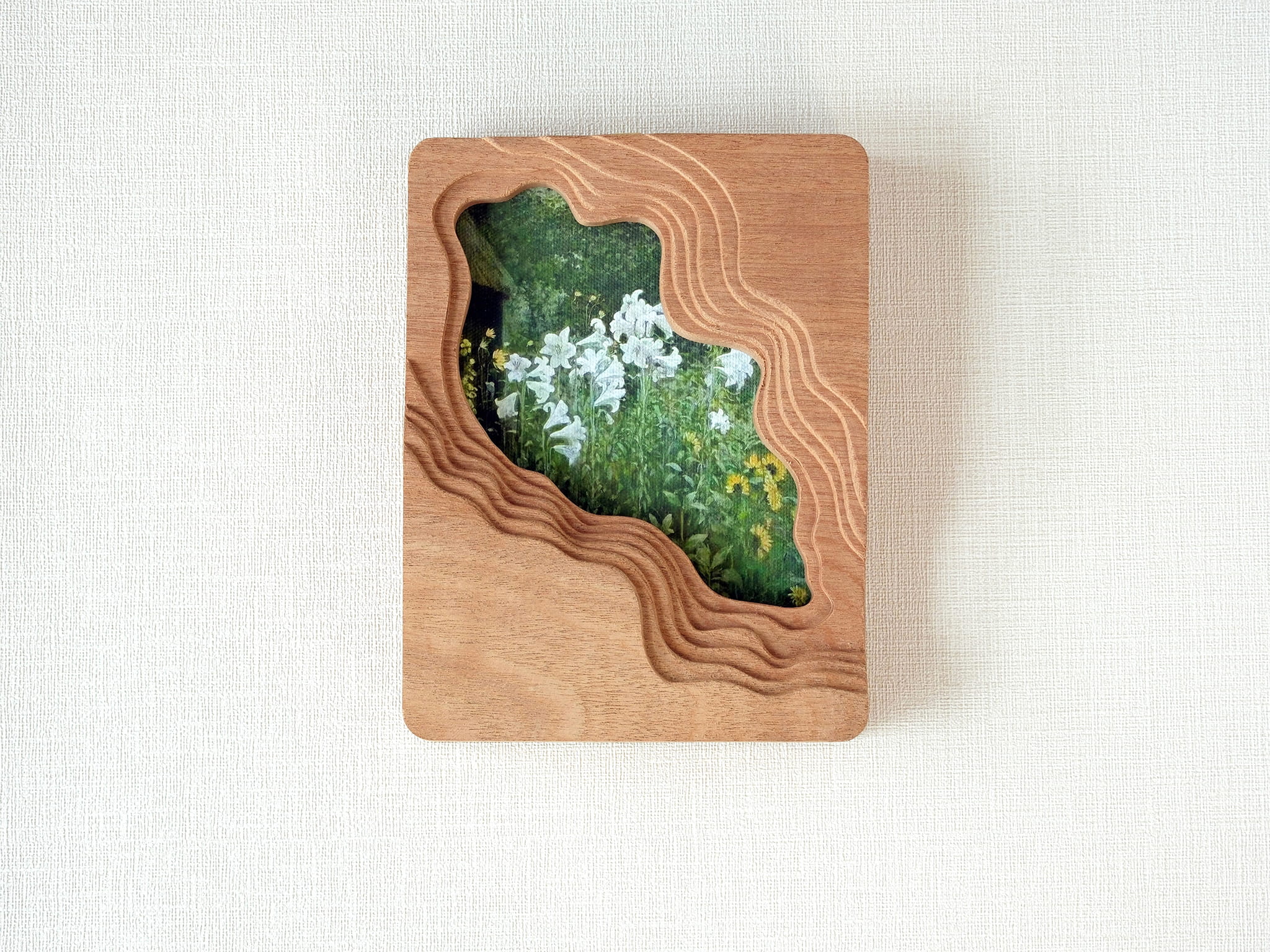 Large handmade solid wood wall art picture frame with flowing stream-shaped cutout and floral meadow artwork, front view.