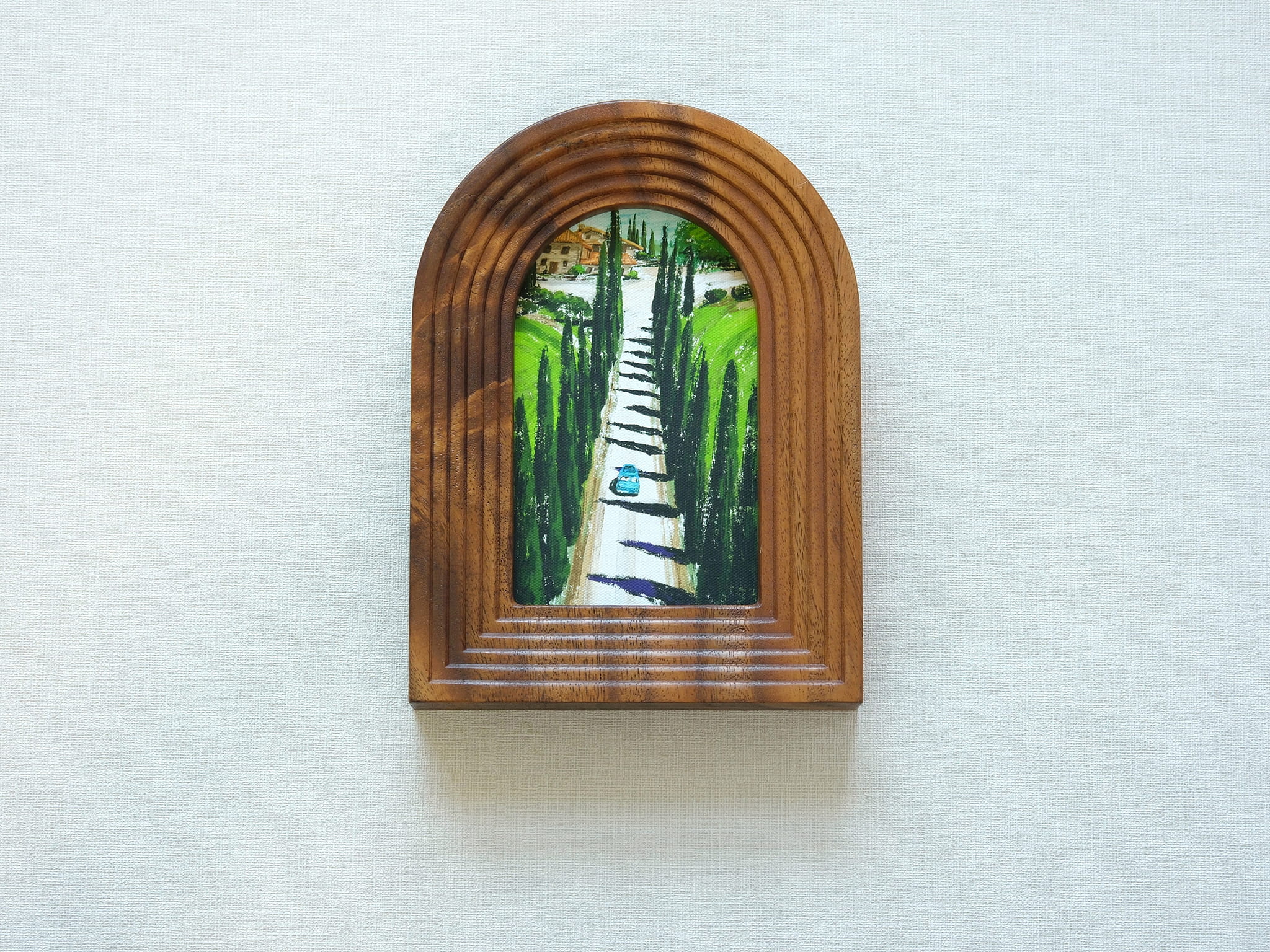 Front view of the arched solid wood frame "Tuscany," featuring a handcrafted stepped border and an oil-style painting of a cypress-lined road leading to an Italian villa.