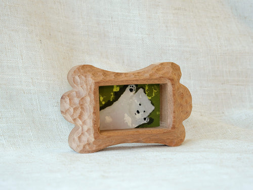 Side-angled view of the bone-shaped wood frame, showcasing its thick profile and hand-chiselled texture on a white backdrop.