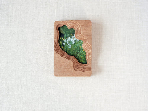 Handmade solid wood picture frame with lake-shaped cutout and floral meadow artwork, front view.
