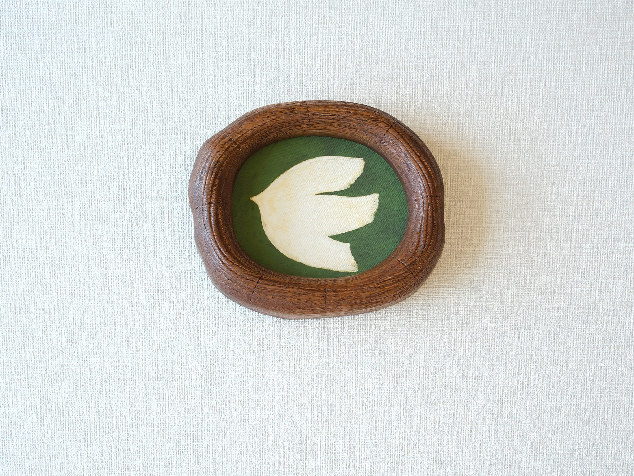 Front view of a Fomjia handcrafted organic-shaped wood frame featuring a minimalist cream dove illustration on a forest green canvas background.