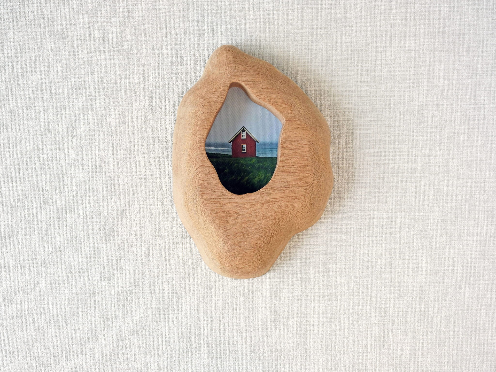 Handmade solid wood wall hanging art picture frame with red house artwork, organic shape front view.