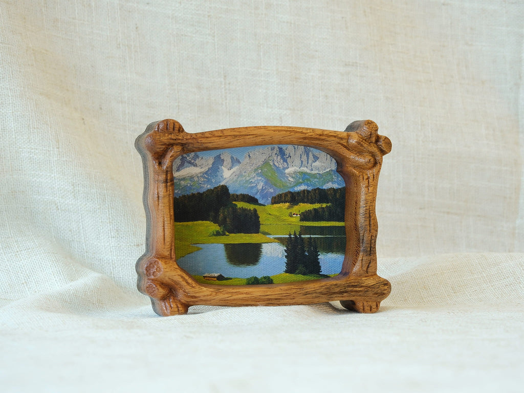 A side-angle view of a handcrafted wood frame with an organic branch-like texture, featuring a vibrant forest sunlight oil painting.