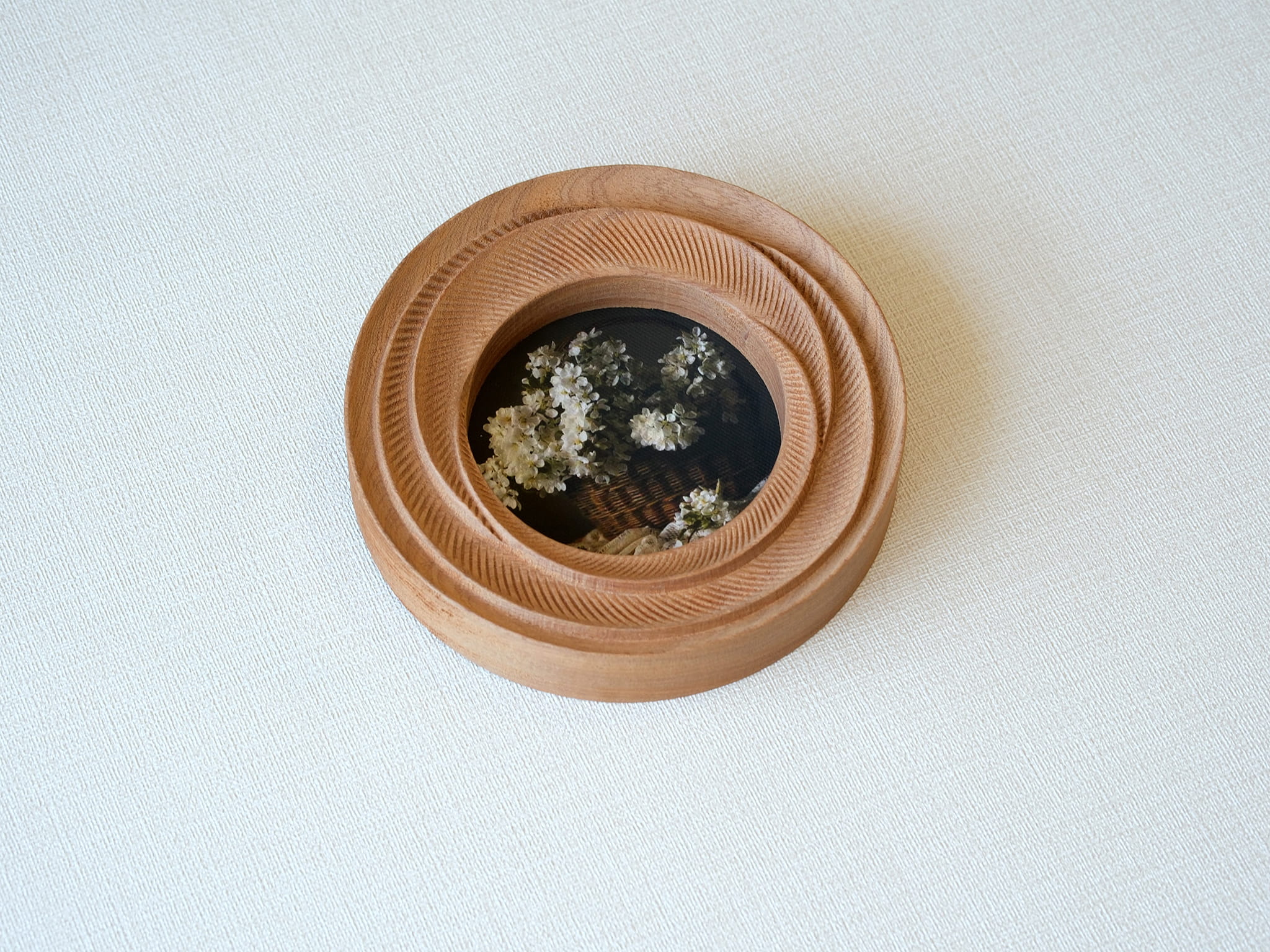 High-angled view of the round flower frame, showing its three-tier stepped design and detailed hand-carved textures.