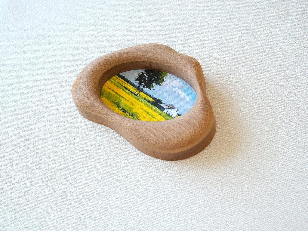 An oblique, high-angle view of the cloud-shaped solid wood frame, showcasing its sculptural depth and the perfectly smooth, hand-sculpted organic curves. The natural wood grain flows continuously across the tactile surface, emphasizing the "Moderno Organico" aesthetic.