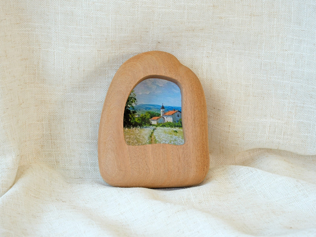 Front view of a house-shaped wood frame, featuring a hand-carved organic silhouette and warm Sapele grain.