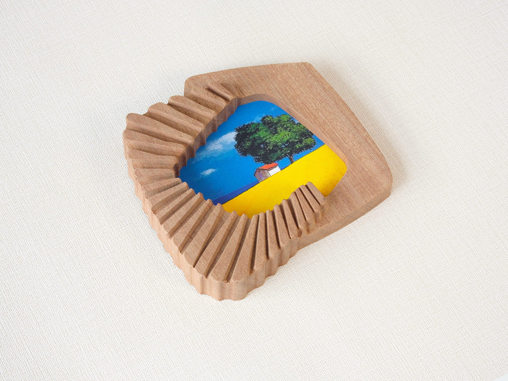 Handmade solid wood wall art picture frame with accordion-inspired shape and landscape artwork, angled side view.