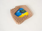 Handmade solid wood wall art picture frame with accordion-inspired shape and landscape artwork, angled side view.