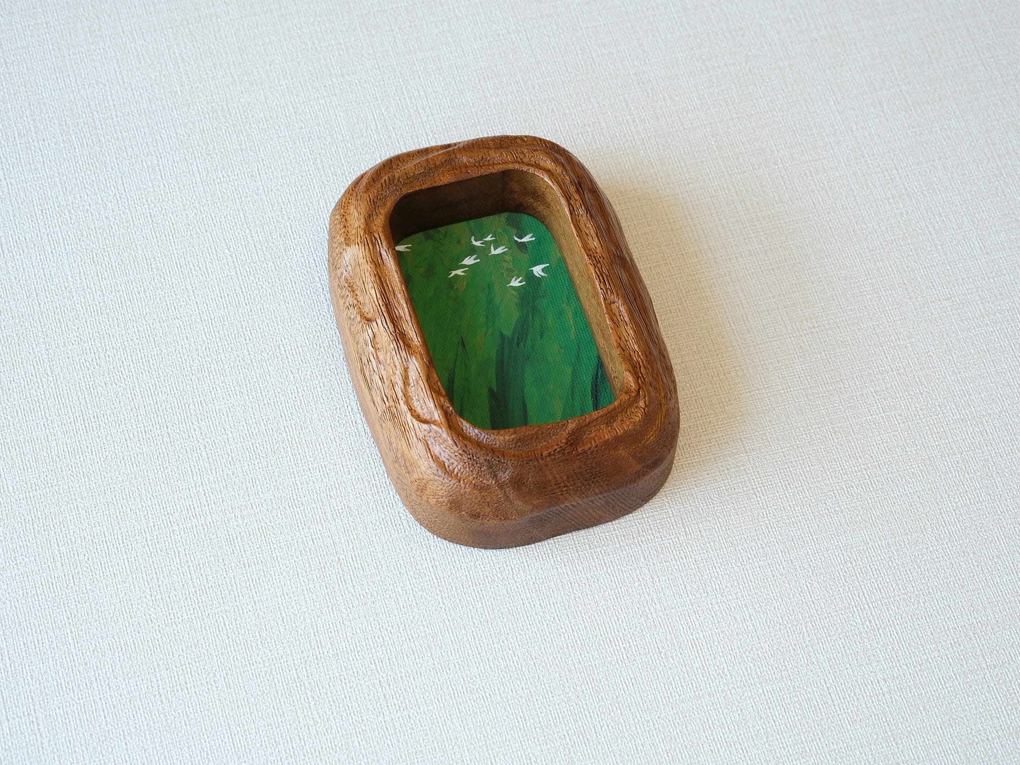Angled top-down view of the rounded rectangle solid wood frame, showing the deep-set art chamber and the bold, natural grain of the thick timber walls.