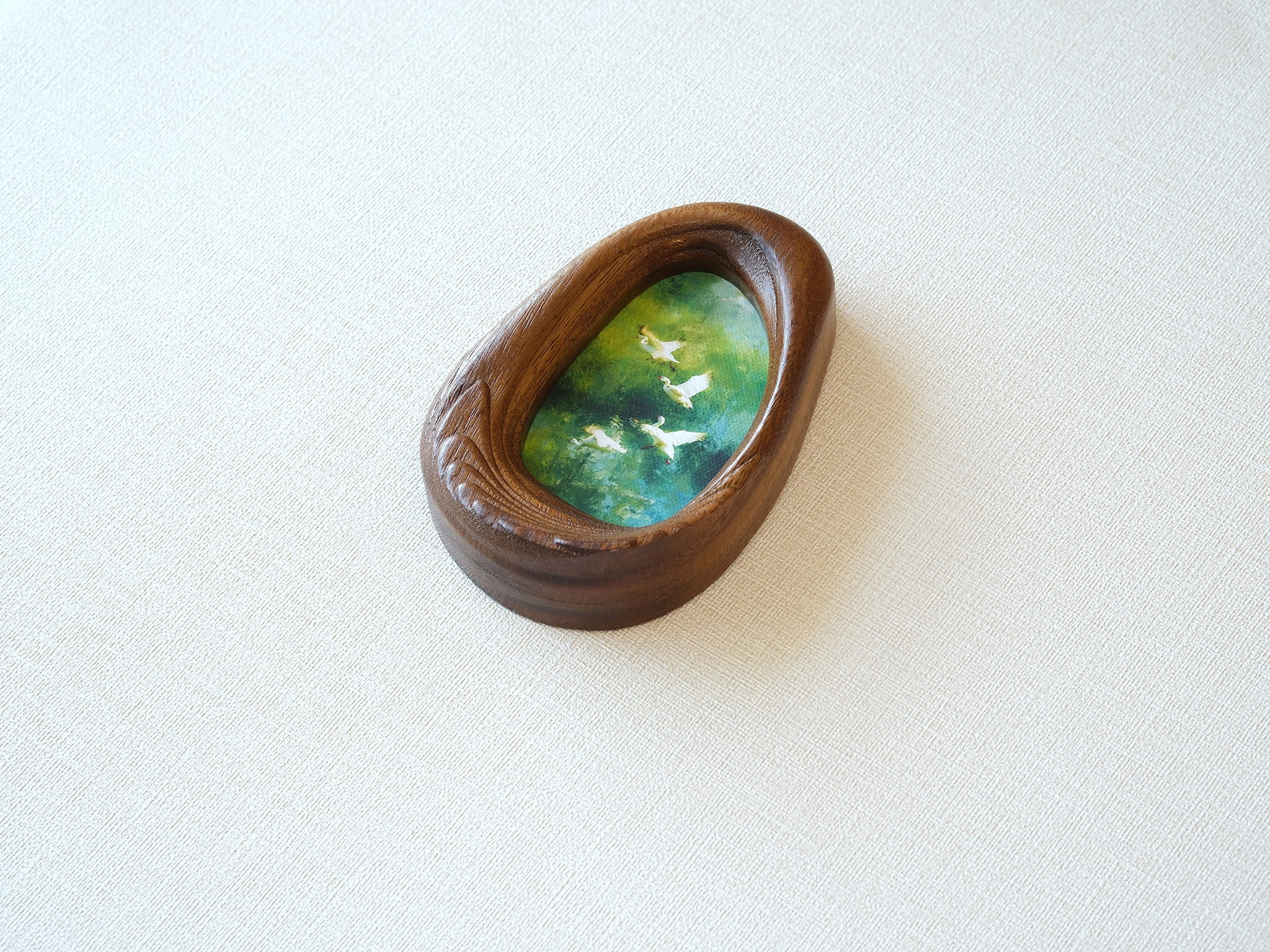 Side view of the Waterdrop handmade solid wood art frame, showcasing the thick pebble-like profile, smooth hand-polished edges, and the depth of the forest birds artwork.