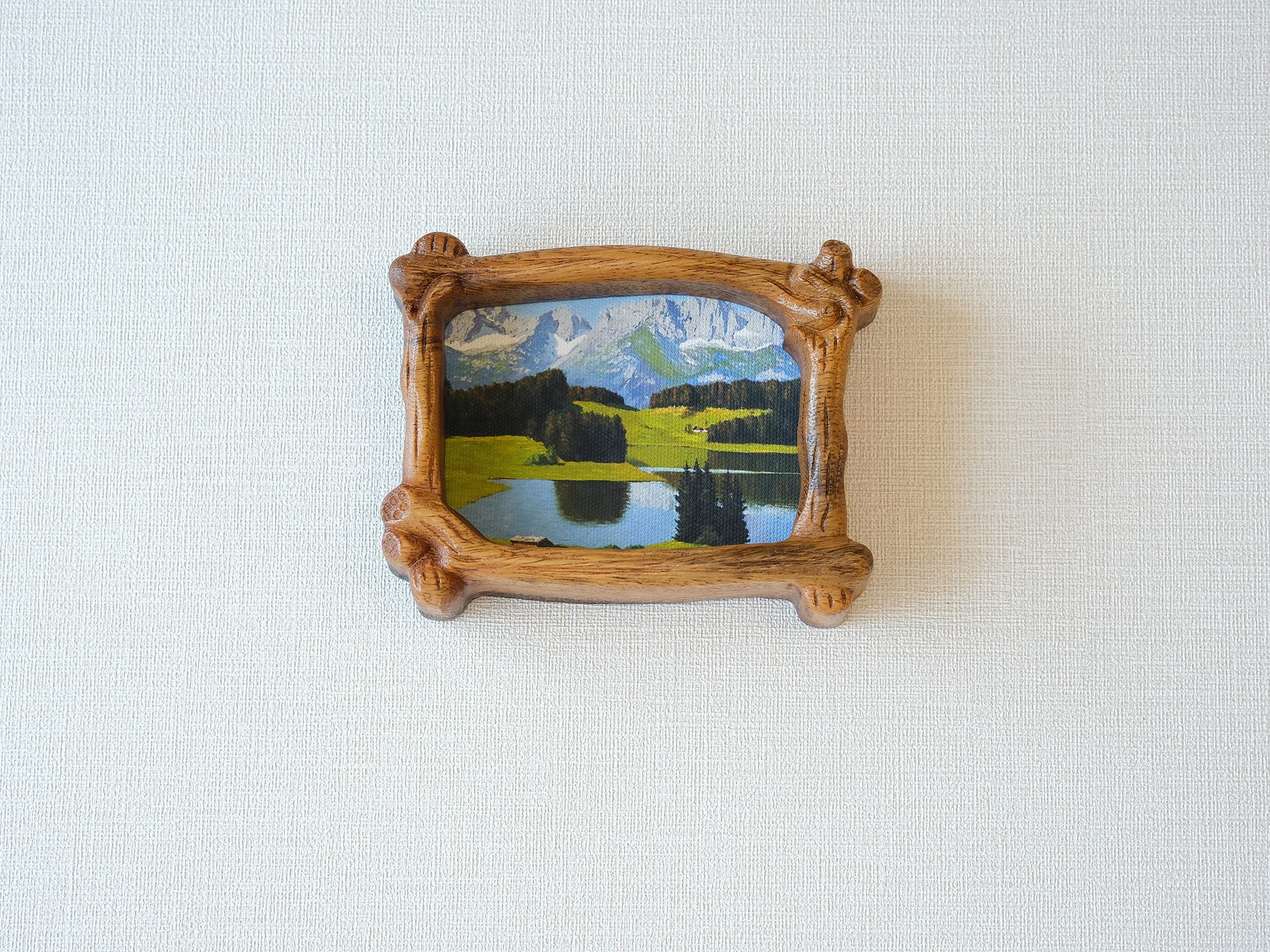 A direct front view of a nature-inspired wood frame with intricate hand-carved bark details, showcasing a lush green forest art piece.