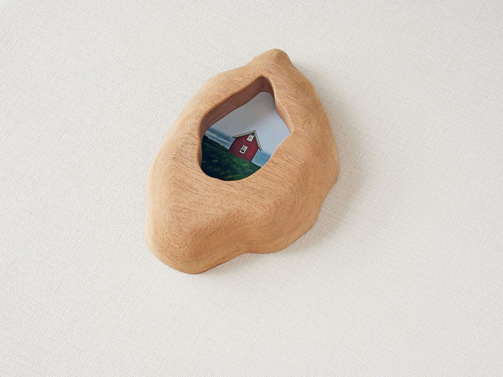 Handmade solid wood wall hanging art picture frame with red house artwork, organic shape side view.